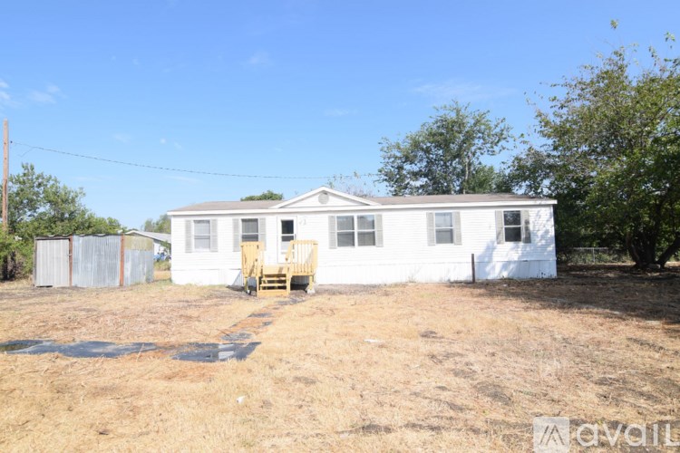 A white house with a porch and a yellow chair in front of it.