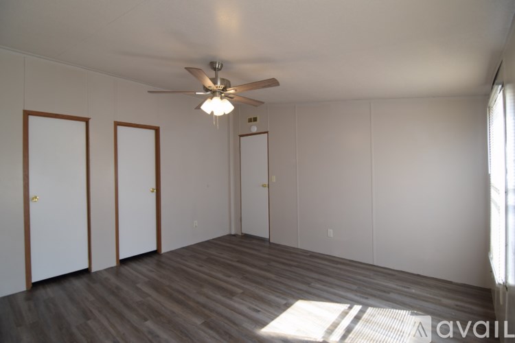 A room with a ceiling fan and three doors.