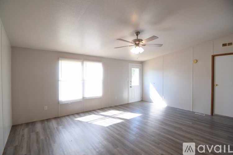A room with a ceiling fan and wooden flooring.