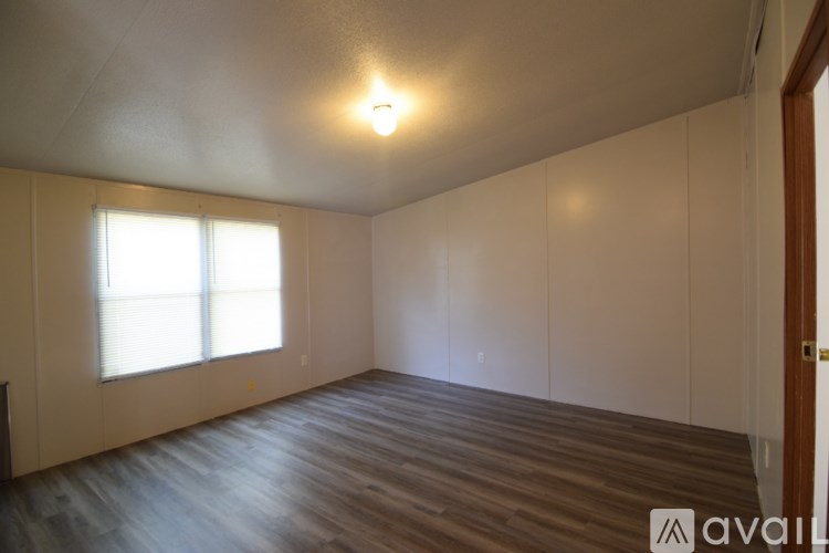A room with wooden flooring and a window with blinds.
