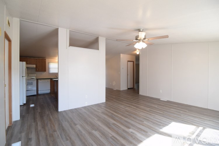 A spacious room with wooden flooring and a ceiling fan.