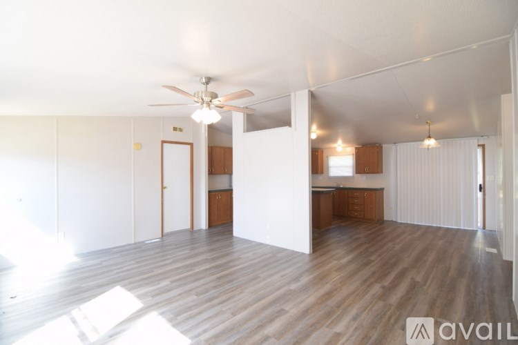 A spacious room with wooden flooring and a ceiling fan.