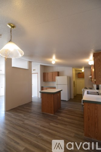 A kitchen with wooden floors and a white refrigerator.