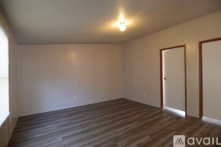 A room with wooden flooring and a single light bulb on the ceiling.