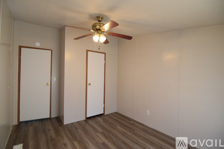 A room with a ceiling fan and three doors.