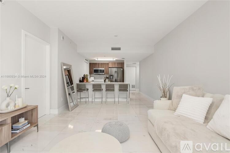 A modern living room with a white couch and a dining area in the background.