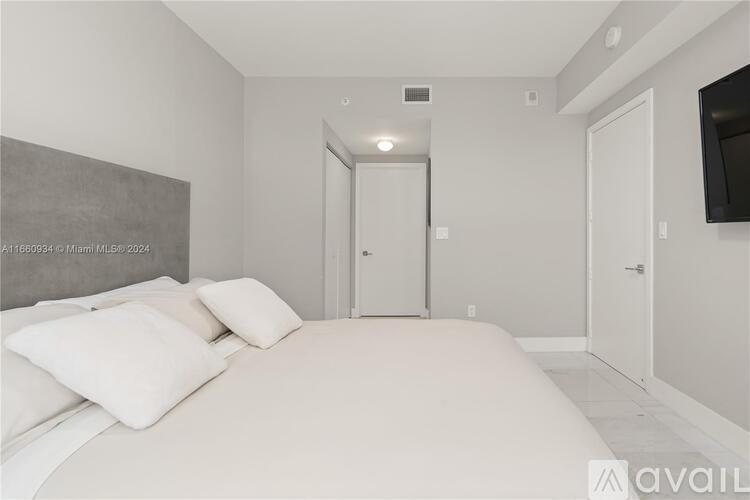 A bedroom with a large bed and a flat screen TV mounted on the wall.