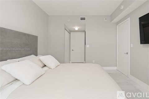A bedroom with a large bed and a flat screen TV mounted on the wall.
