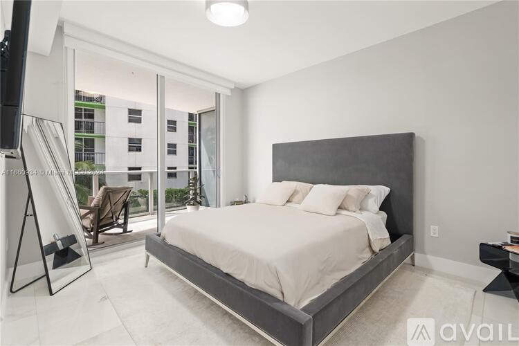 A bedroom with a large bed and a balcony overlooking a building.