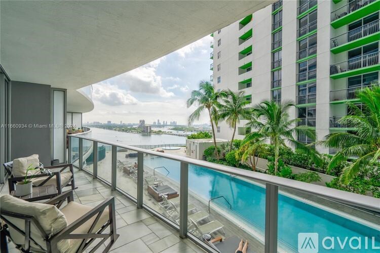 A balcony with chairs and a pool overlooking a cityscape.