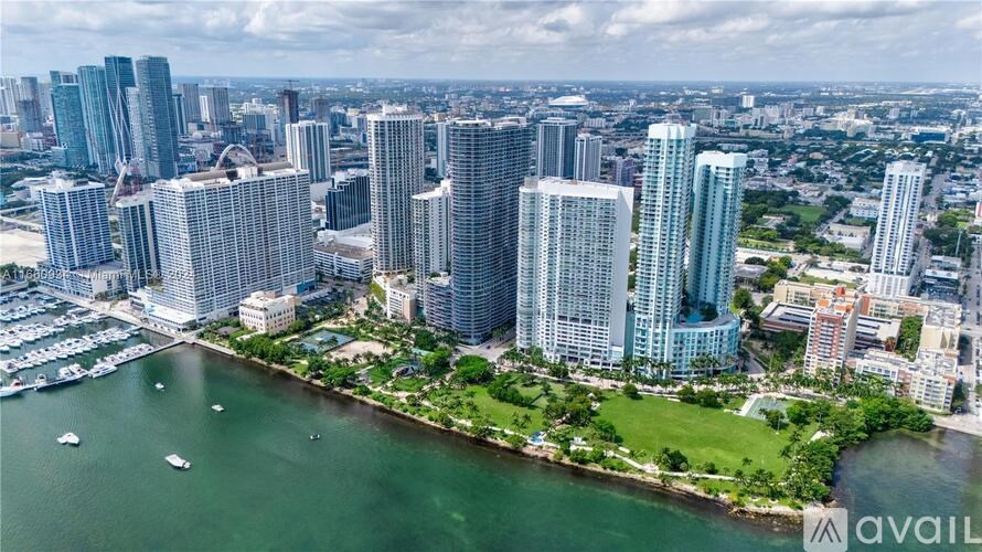 A cityscape with tall buildings and a body of water in the foreground.