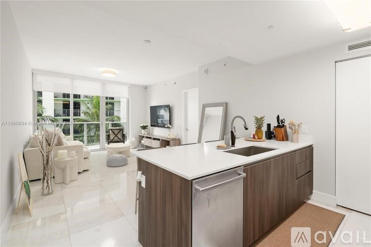 A modern kitchen with a large island and a dining area with chairs.