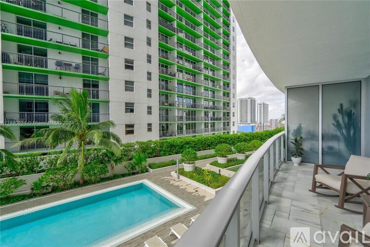 A balcony with a pool and a view of a green building.