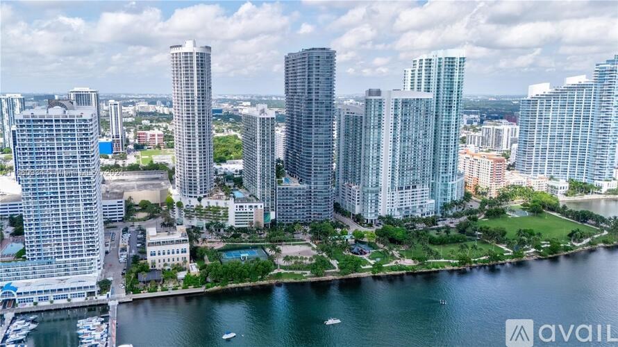 A cityscape with tall buildings and a body of water in the foreground.