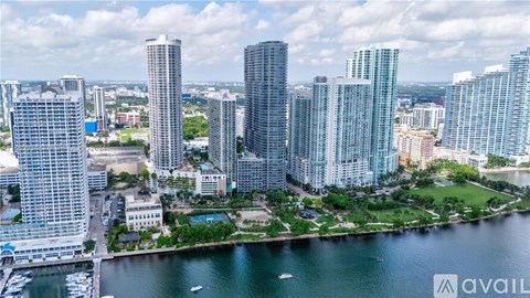 A cityscape with tall buildings and a body of water in the foreground.