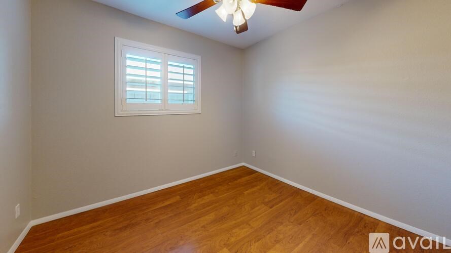 A room with wooden floors and a ceiling fan with a light.