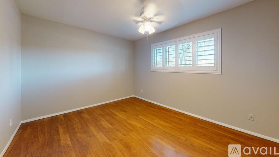 A room with wooden flooring and a ceiling fan.