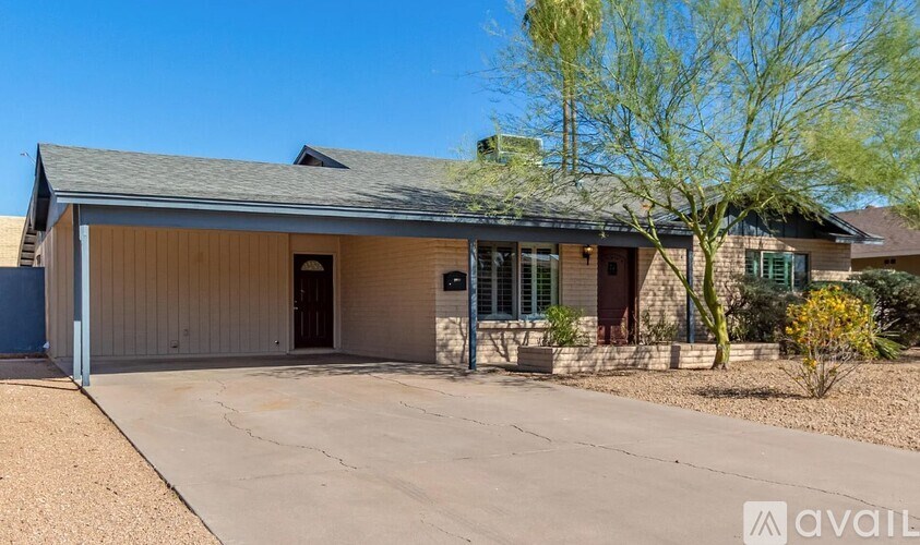 A house with a garage and a tree in front.