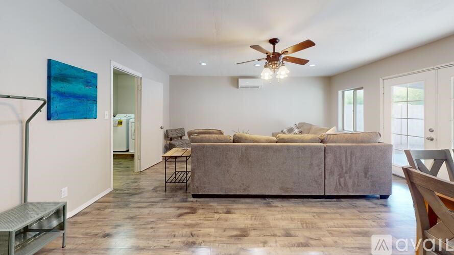 A living room with a grey couch and a ceiling fan.