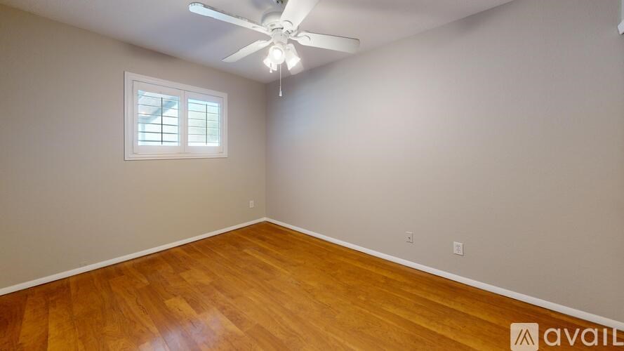 A room with wooden flooring and a ceiling fan.