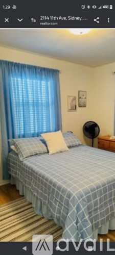 A bedroom with a bed covered in a blue and white checkered comforter.
