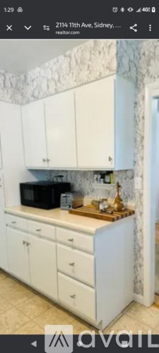 A kitchen with white cabinets and a microwave on the counter.
