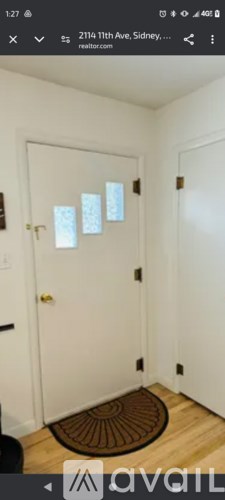 A white door with a keypad and a brown doormat.