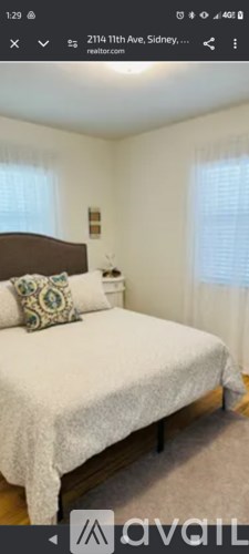 A bedroom with a bed, nightstand, and window.