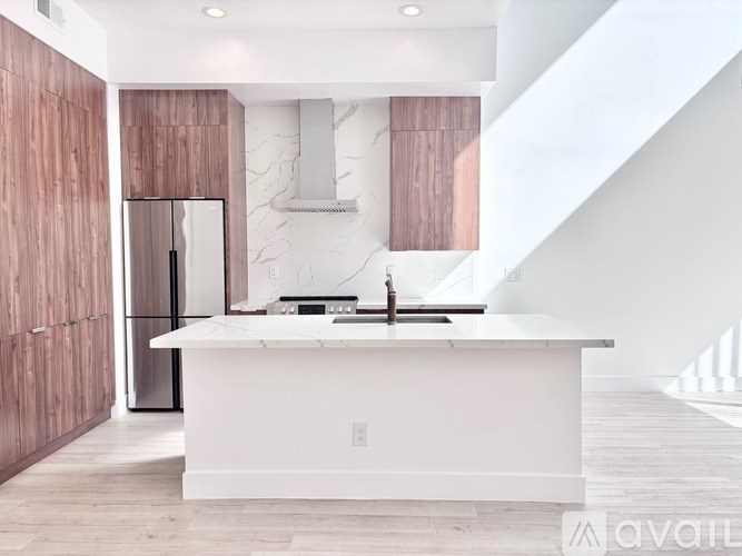 A modern kitchen with a white countertop and wooden cabinets.