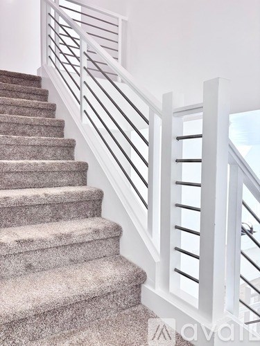 A staircase with a white railing and beige carpeted steps.
