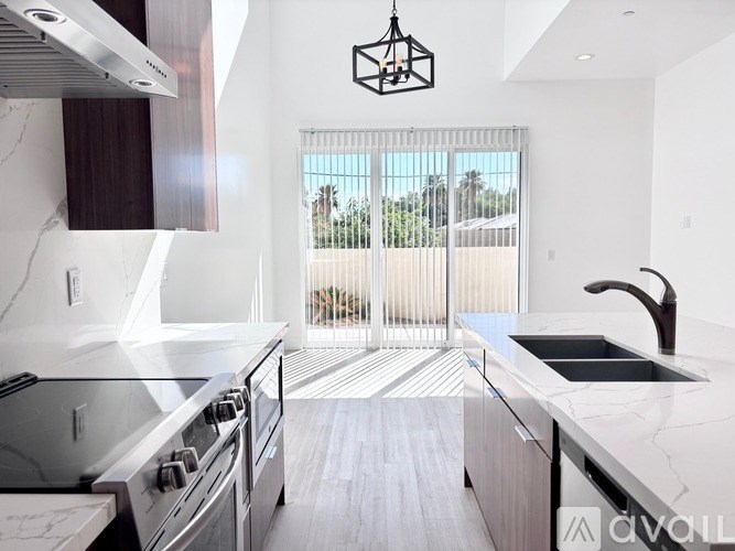 A modern kitchen with a stainless steel stove and a view of the outdoors through the sliding glass doors.