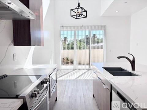 A modern kitchen with a stainless steel stove and a view of the outdoors through the sliding glass doors.