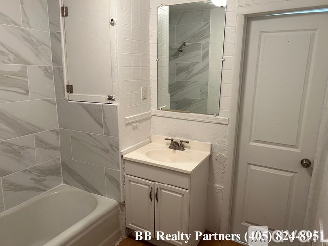 A bathroom with a marble tile wall and a white sink.