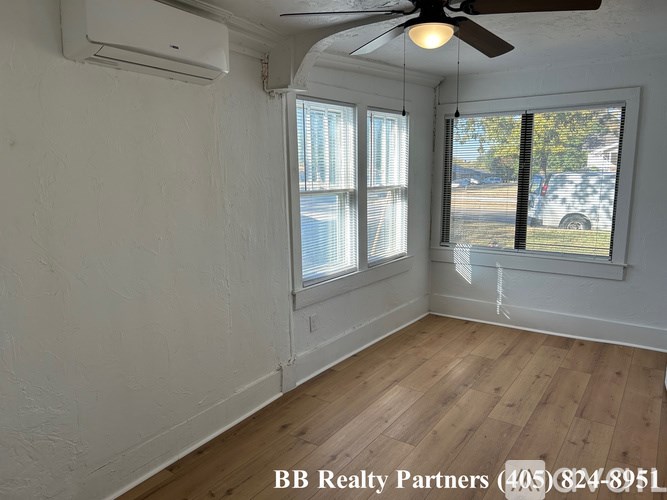 A room with a ceiling fan and a window overlooking a street.