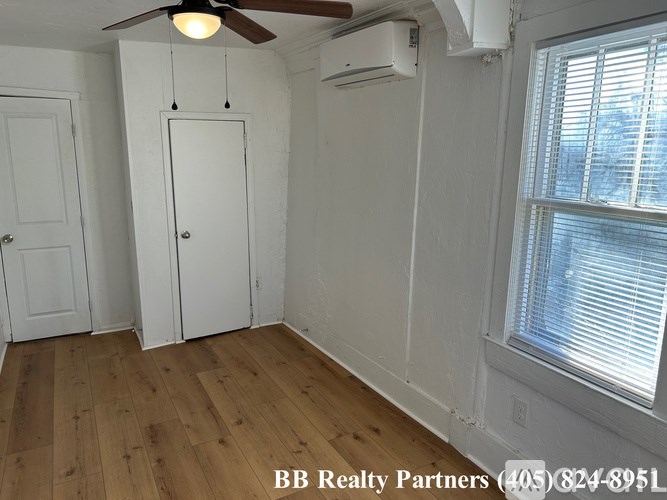 A room with a ceiling fan, two doors, and a window with blinds.