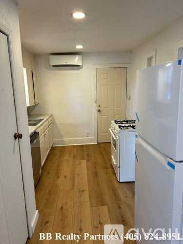 A kitchen with a white refrigerator and wooden floors.