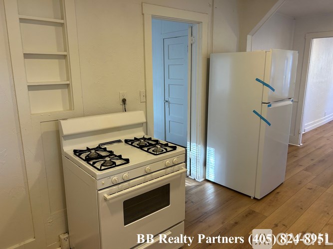 A white stove and oven in a kitchen with a blue door in the background.