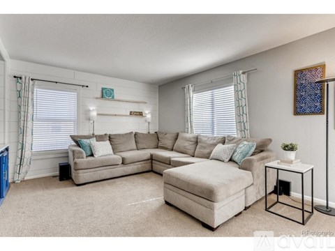A living room with a beige sofa and a small white table.