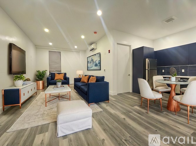 A living room with a white sofa, a white coffee table, and a TV on the wall.