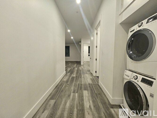 A long hallway with a washer and dryer on the side.