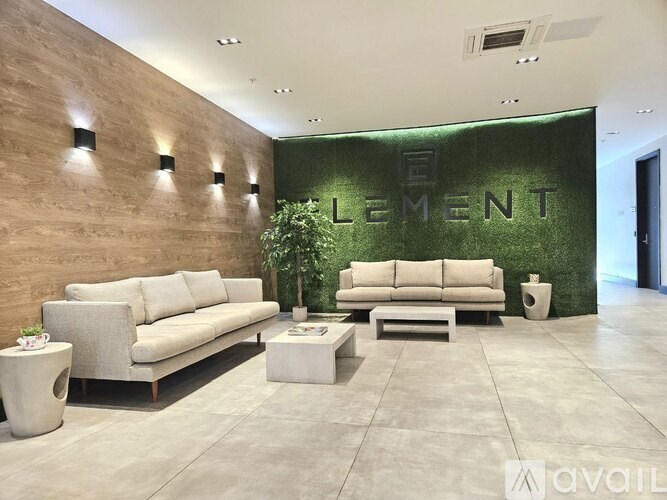 A living room with a couch, a coffee table, and a green wall with the word "ELEMENT" on it.