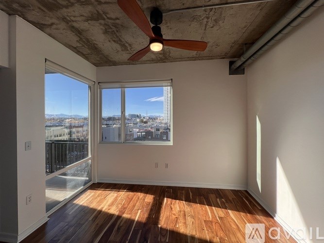A room with a ceiling fan and a view of the city.