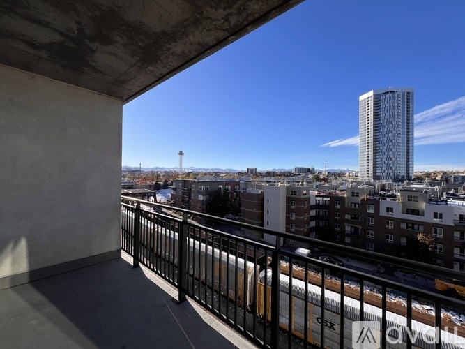 A balcony with a view of a cityscape and a train.