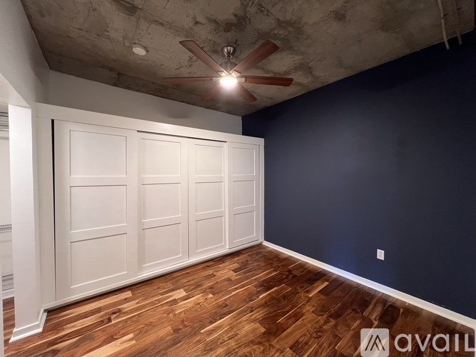 A room with a white door and a ceiling fan.