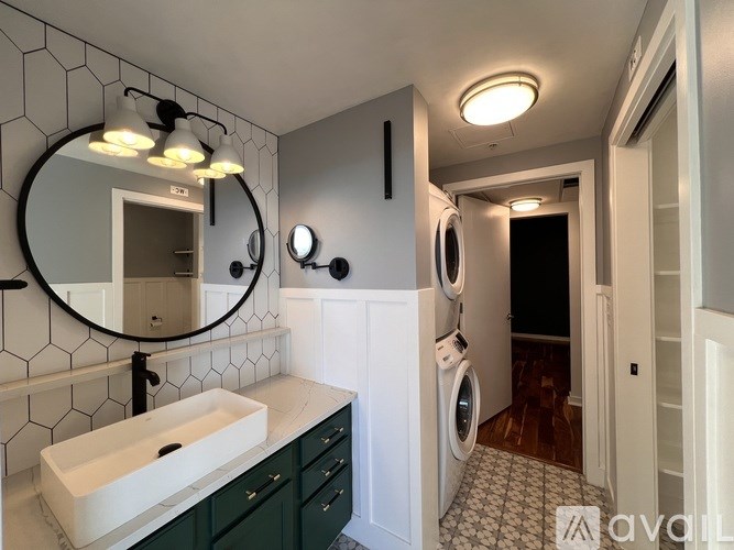 A bathroom with a white sink and a mirror with lights above it.