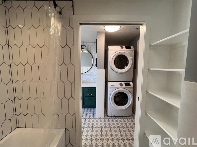 A bathroom with a white tiled wall and a white washing machine.