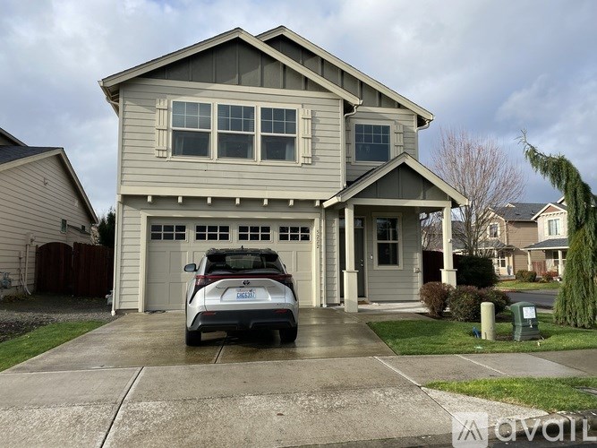 A house with a grey car parked in front.