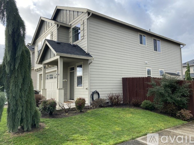 A house with a grey exterior and a white door is for sale.