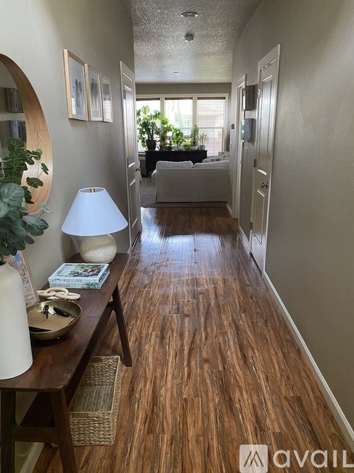 A hallway with wooden floors and a lamp on a table.