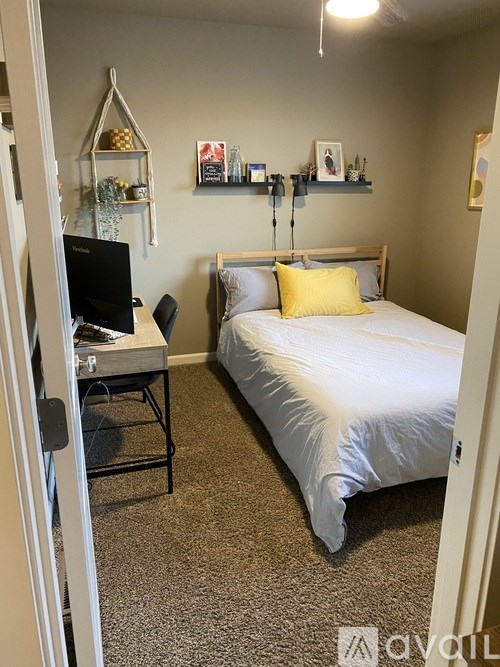 A bedroom with a bed, desk, and shelves.